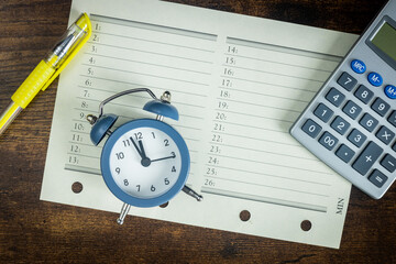 Office organizer with a calculator and an alarm clock set for five to twelve, the concept of...