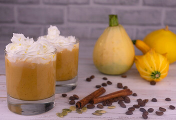 Two glasses with pumpkin latte, spices and whipped cream.