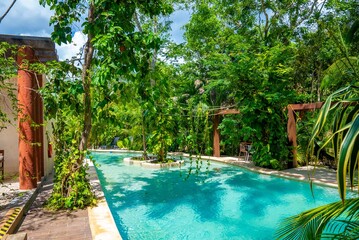Beautiful swimming pool amidst lush green trees with architectural columns and hammock at luxury hotel resort