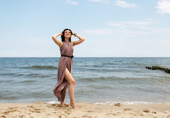 young brunette woman stands on the sand by the sea
