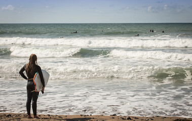 Black Rock Beach, Widemouth Bay in Bude Cornwall UK -  female surfer watching the surfers