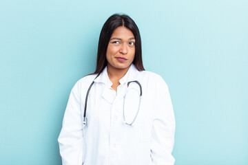 Young doctor Venezuelan woman isolated on blue background confused, feels doubtful and unsure.