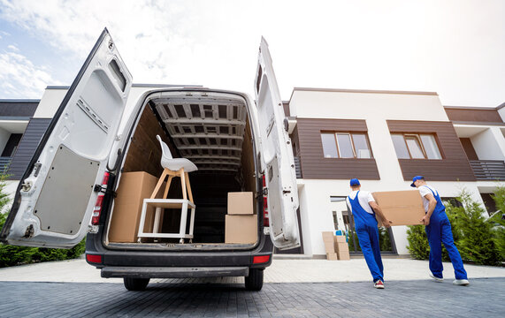 Two removal company workers unloading boxes and furniture from minibus