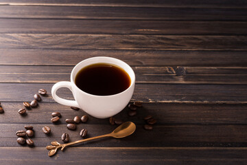 Coffee cup with black coffee and coffee beans on wooden table background, top view