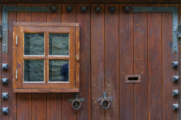 Detail of medieval wooden door with small window and metal fittings.