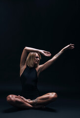 Fototapeta na wymiar a forty-year-old woman in excellent physical shape with elastic muscles and healthy skin performs yoga exercises on a dark background. Studio photography. excellent health at forty.