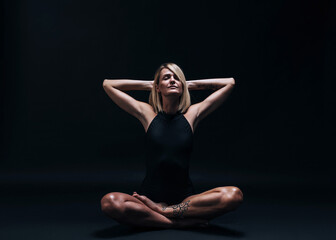 Fototapeta na wymiar a forty-year-old woman in excellent physical shape with elastic muscles and healthy skin performs yoga exercises on a dark background. Studio photography. excellent health at forty.