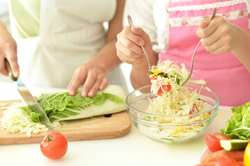 Close up portrait of girl with her mother cooking together at kitchen table