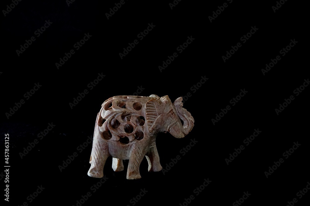 Wall mural small east Asian elephant statuette from a tourist souvenir shop on black background