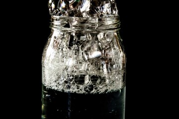 soap bubbles overflowing a glass of water on dark background