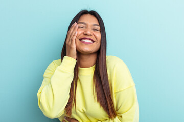 Young Venezuelan woman isolated on blue background laughs happily and has fun keeping hands on...