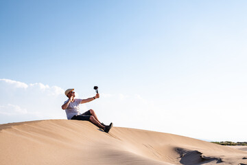 Man sitting and taking selfies on sand dune