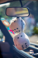 Vertical shot of fluffy dice hanging from the vehicle mirror
