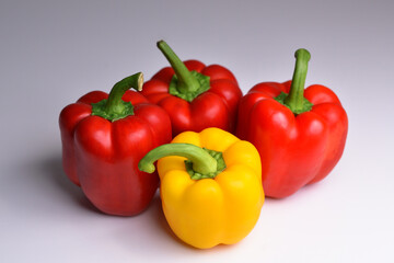 Isolated peppers. Four bell peppers of different colors (red, yellow,)  isolated on grey background. Colorful red and yellow peppers paprika background