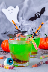Halloween cocktail with green bubble drink and candy worms, vertical
