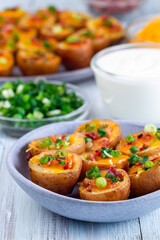 Mini red skinned loaded potatoes with crispy bacon, scallions and sharp cheddar cheese, closeup
