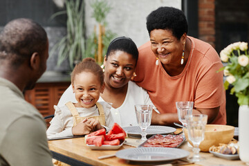 Portrait of happy African-American family enjoying dinner together outdoors at terrace, copy space
