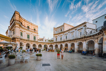 Largo Piazza Maria Immacolata in the historic center of Martina Franca at sunset with people walking around - obrazy, fototapety, plakaty