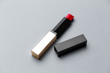 Luxury red lipstick on a neutral grey background. Promotion of luxury fashion cosmetic brand. The concept of fashion and beauty. Top view. Flat lay. Copy space. Fashion blog design