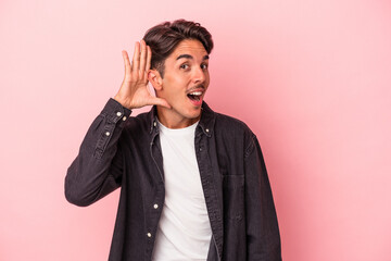 Young mixed race man isolated on white background trying to listening a gossip.