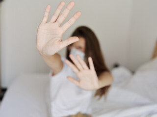 woman gesturing with hands sitting on bed medical mask isolated room quarantine model