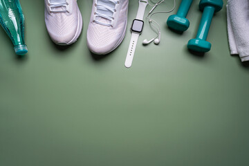Flat lay sport with shoes, bottle of water, dumbbells, watch, and earphones on green background. Concept healthy lifestyle, sport and diet