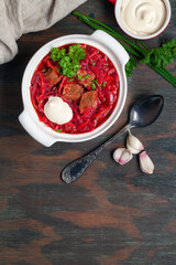 Traditional Russian or Ukrainian red soup with beef and vegetables-beet, potato, carrot, cabbage, onion, fresh herbs and spices. Served with garlic pampushkas and sour cream. Borscht. Top view