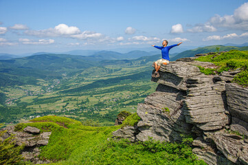 A man in a blue T-shirt sits on a high bench with his arms outstretched to the side. Ukraine Carpathians