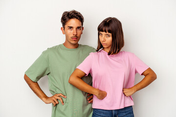 Young mixed race couple isolated on white background frowning face in displeasure, keeps arms folded.