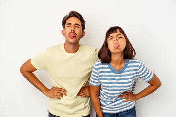 Fototapeta premium Young mixed race couple isolated on white background funny and friendly sticking out tongue.