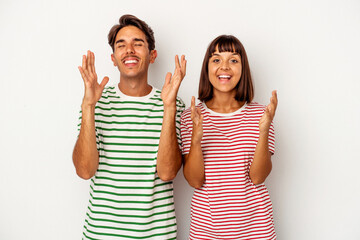 Young mixed race couple isolated on white background laughs out loudly keeping hand on chest.