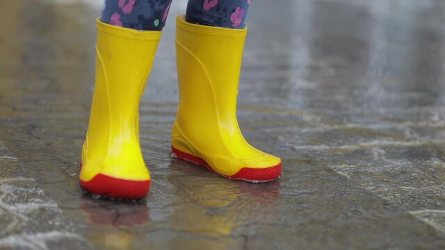 Child walk in the rain in rubber boots