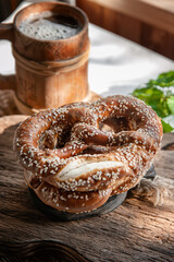 Fresh pretzel on a rustic wooden table with a wooden beer mug. Rustic style