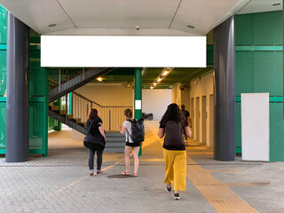 People walking toward train station with white billboard