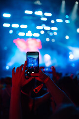 Hand with a smartphone records live music festival, Taking photo of concert stage, live concert.  Youth, party, vacation concept.
