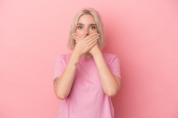 Young caucasian woman isolated on pink background shocked covering mouth with hands.