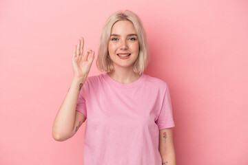 Young caucasian woman isolated on pink background cheerful and confident showing ok gesture.