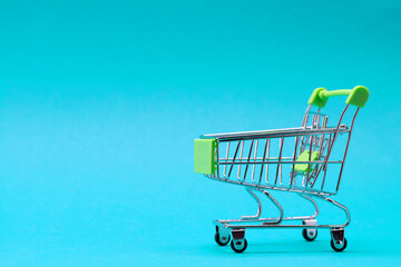 Shopping trolley on a blue background. Green color. Place for an inscription. Shopping concept