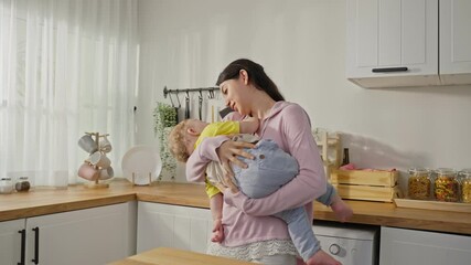 Caucasian busy mother doing hold baby boy toddler to lull him to sleep