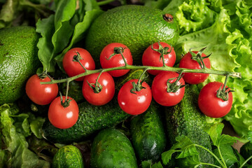 Vegetarian still life. Raw vegetables. Red tomatoes on a green background.