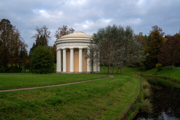 Obraz premium View of the Temple of Friendship on the bank of the Slavyanka River in the Pavlovsky Palace and Park Complex on an autumn cloudy morning, St. Petersburg, Russia