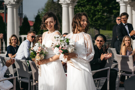 Candid shot of two female lesbian LGBT brides walking through guests