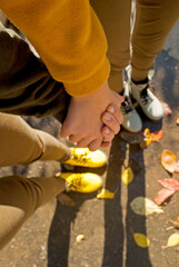 Autumn mood. Two girls in bright shoes stand in a puddle after the rain and hold hands. 