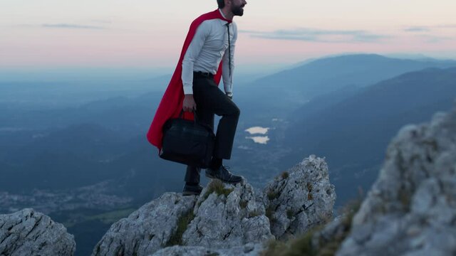 Businessman with the mantle of a superhero over the mountain.