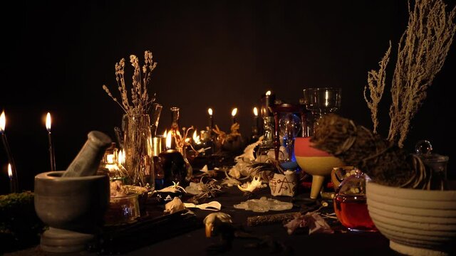Occult and esoteric witch doctor still life. Halloween background with magic objects. Black candles, skull, crystal stones, and potions vials on witch table. Mystic witchery background with weeds.