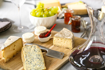 repas de différents fromages accompagné de confiture raisin et vin rouge sur une table
