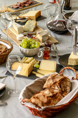 repas de différents fromages accompagné de confiture raisin et vin rouge sur une table