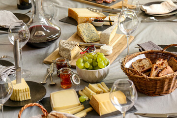 repas de différents fromages accompagné de confiture raisin et vin rouge sur une table