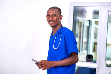 young male doctor holding digital tablet in hospital smiling.