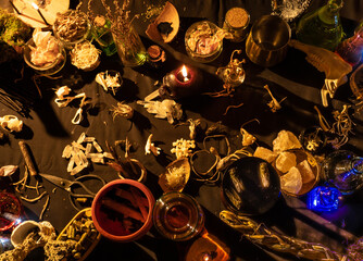 Occult and esoteric witch doctor still life. Halloween background with magic objects. Black candles, skull, crystal stones, and potions vials on witch table. Mystic witchery background with weeds.